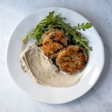 overhead photo of quinoa patties on a plate with hummus
