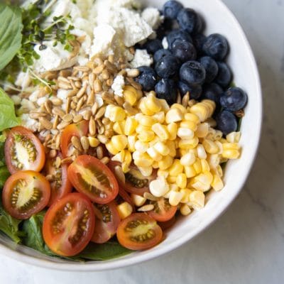 Tomatoes, corn, blueberries and barley in a bowl.