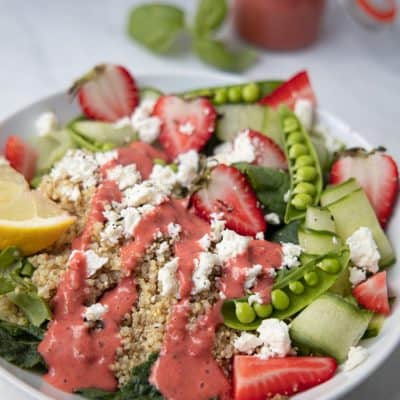 strawberry summer quinoa salad in a bowl with strawberry basil dressing drizzled on top