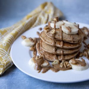stack of banana oat pancakes drizzled with almond butter
