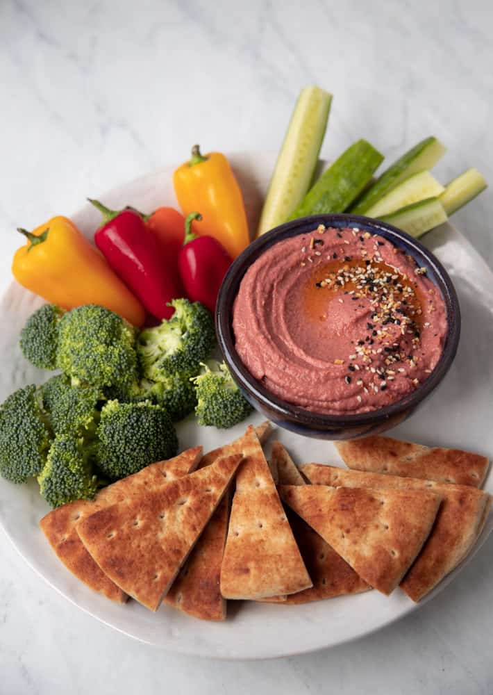 platter of fresh cut veggies and a bowl of beet hummus