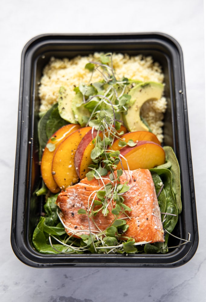 salmon peach bowl in a black meal prep container