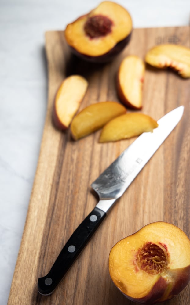 juicy peaches sliced up on a cutting board