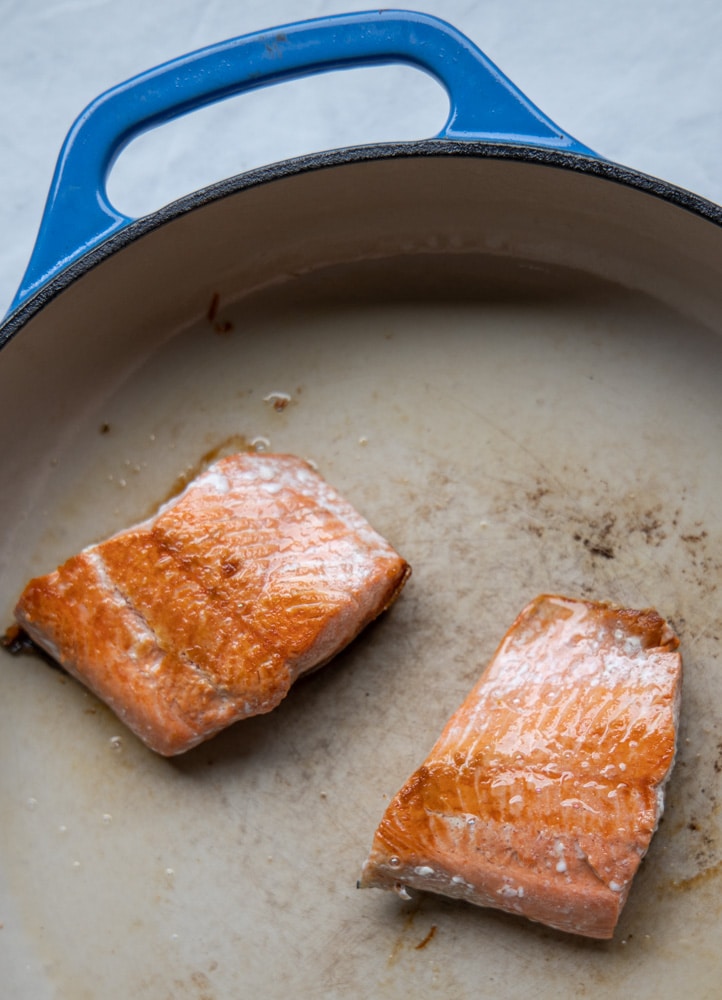 salmon filets being seared in a pan