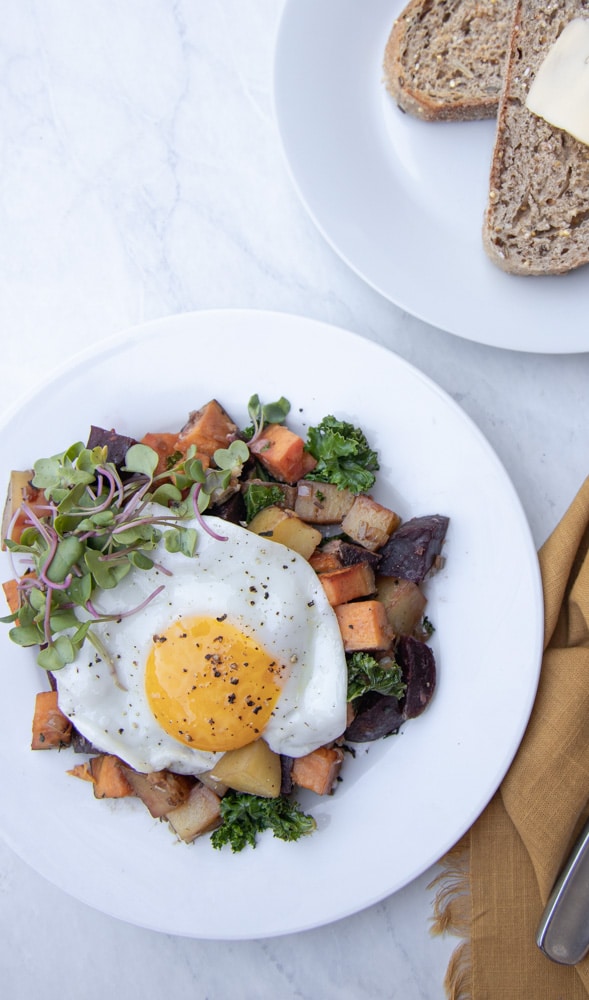 plate with root vegetable hash and topped with sunny side up egg.