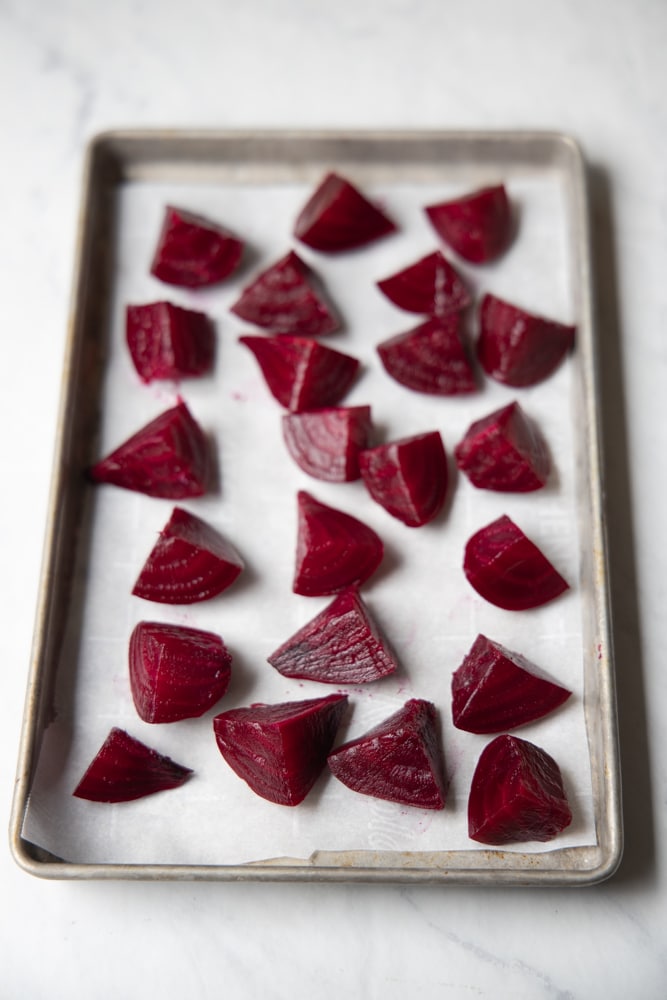 quartered beets on a sheet tray with parchment paper, ready for the freezer