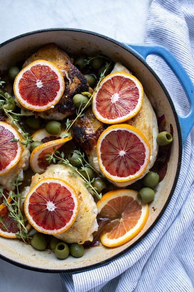 skillet with chicken thighs topped with blood orange slices