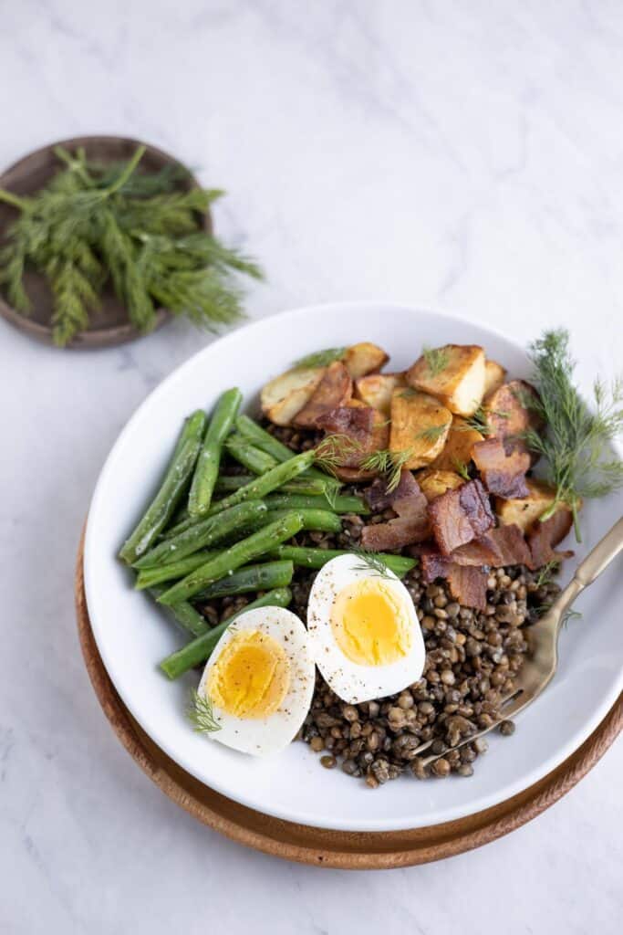 bowl with lentils, green beans, hardboiled eggs, potato and crispy bacon