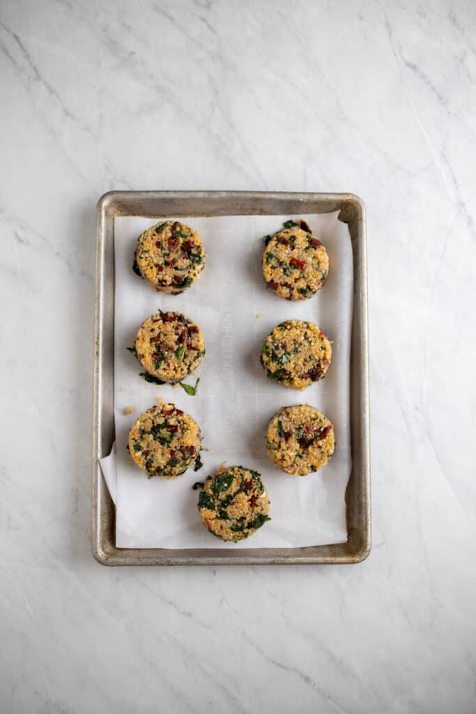 prepped raw sundried tomato and Swiss chard quinoa cakes on a cookie sheet