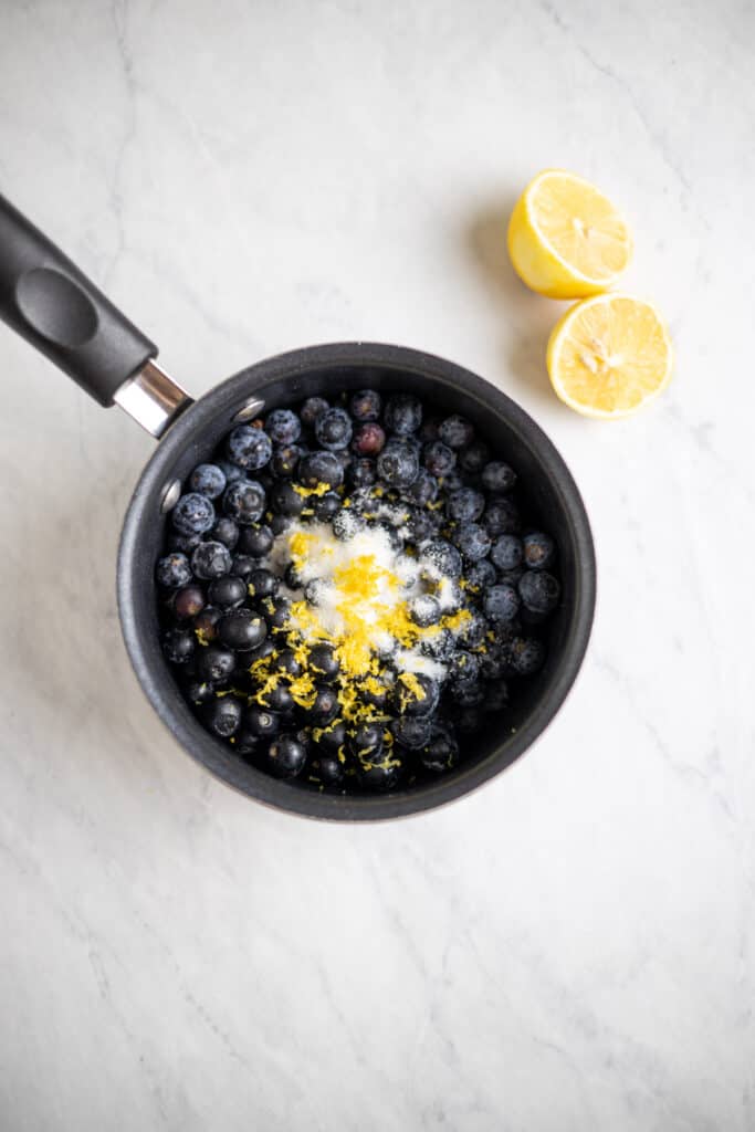 saucepot of blueberries and sugar topped with lemon zest