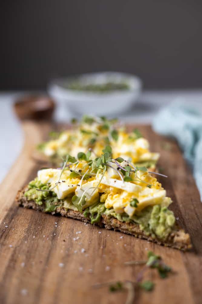 open face toast topped with mashed avocado and egg salad