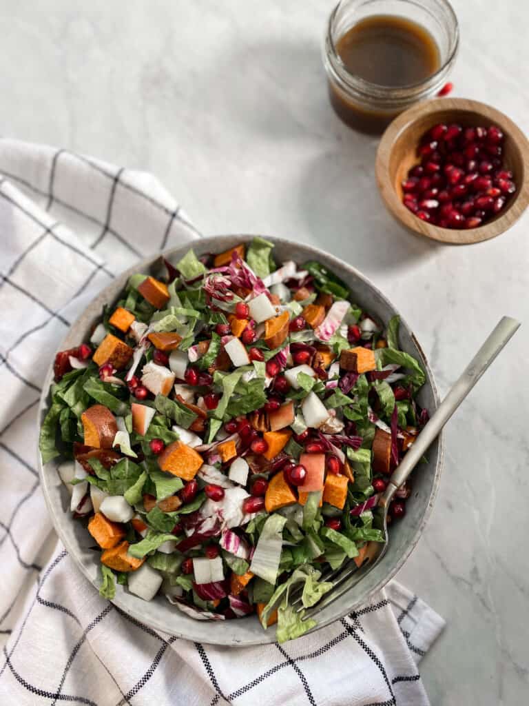 Bowl filled with fall chop salad, topped with pomegranate seeds