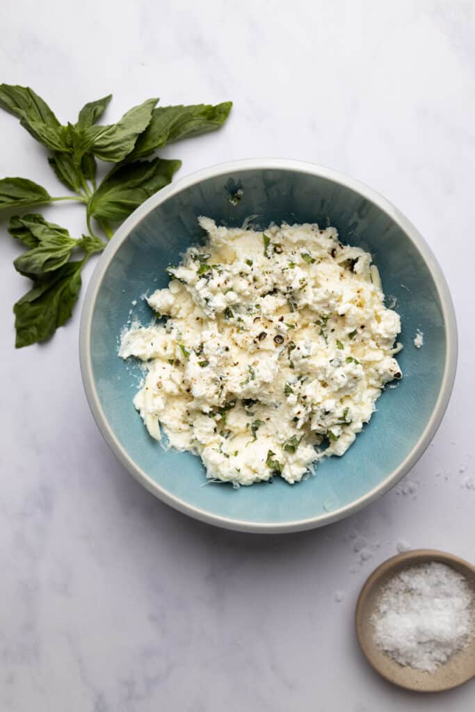 blue bowl with ricotta, mozzarella and parmesan cheese mixture.