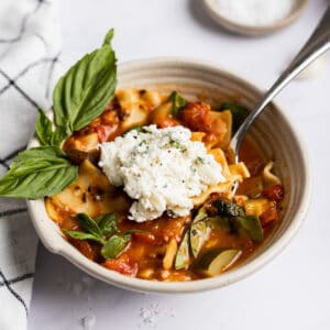 Vegetarian lasagna soup in a bowl with ricotta cheese on top.