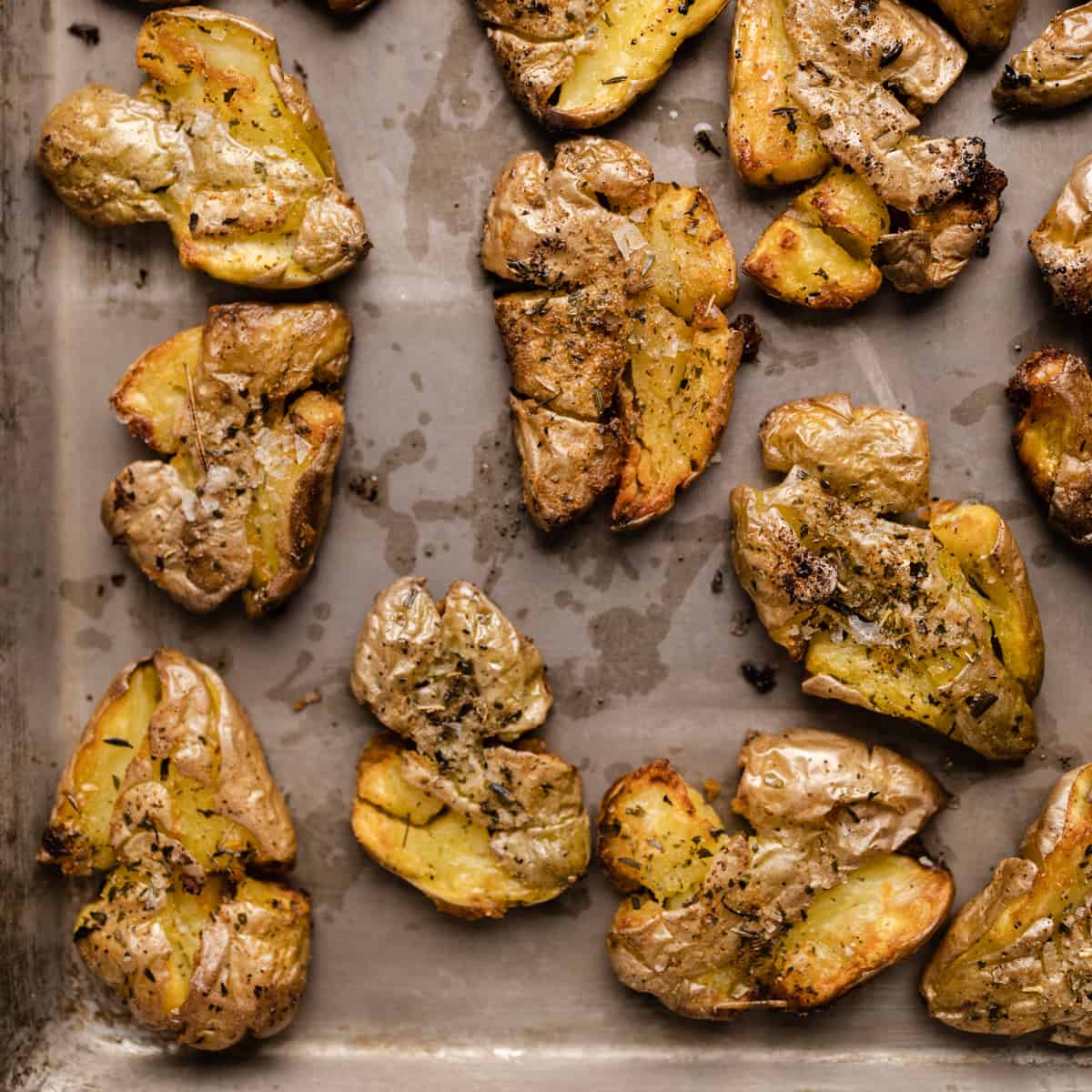 Golden brown smashed fingerling potatoes on a cookie sheet.