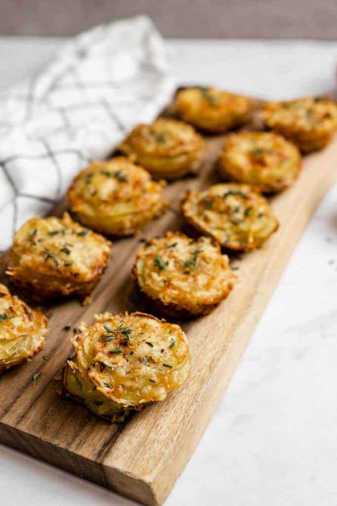 Cheesy gruyere and thyme potato stacks on a wooden platter.