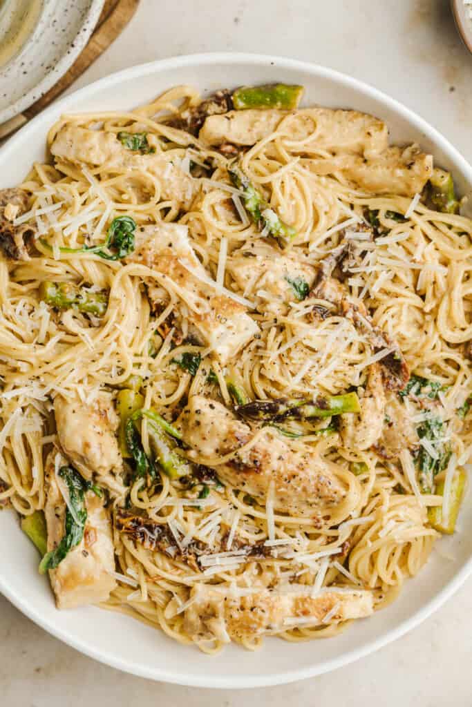 Sun dried tomato pasta chicken in a white serving bowl.