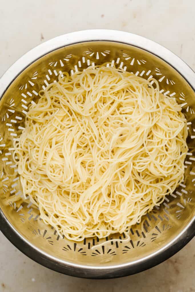 Angel hair pasta drained in a collander.