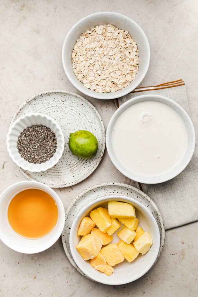 Ingredients to make tropical overnight oats with frozen fruit in individual bowls.