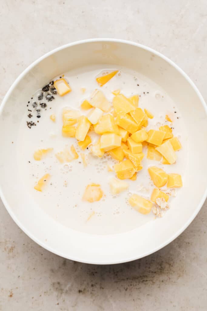 Mixing bowl with frozen fruit and ingredients added to it.