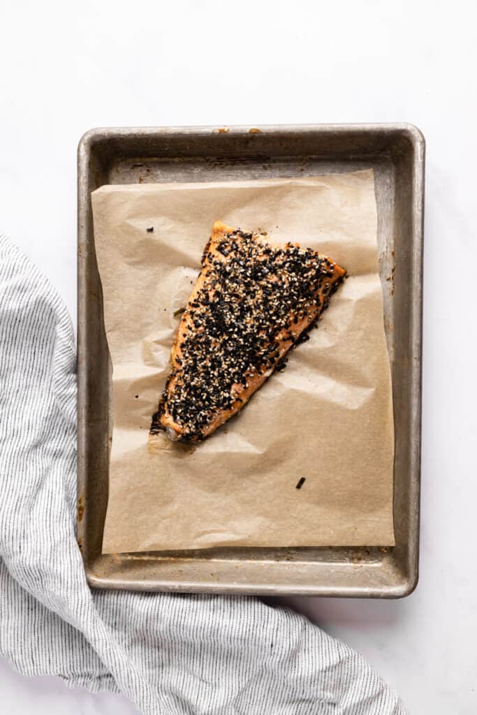 Cooked furikake salmon filet on a sheet pan with parchment paper.