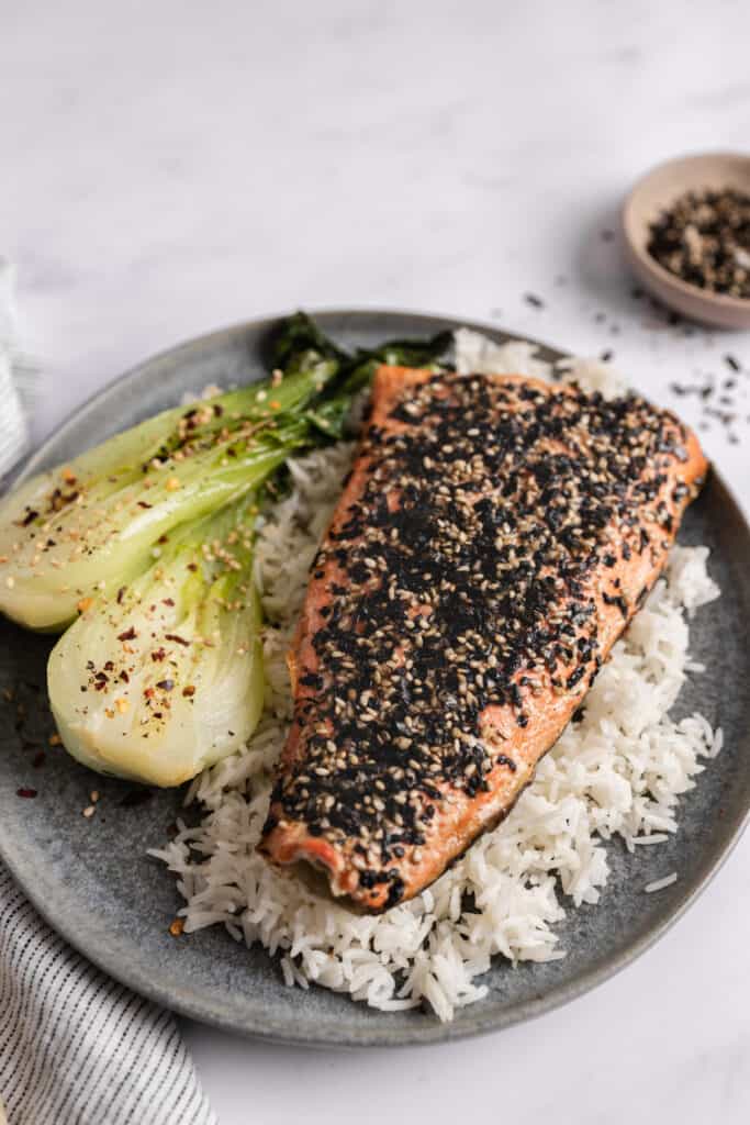 Whole furikake salmon filet on a bed of white rice with a side of bok choy.